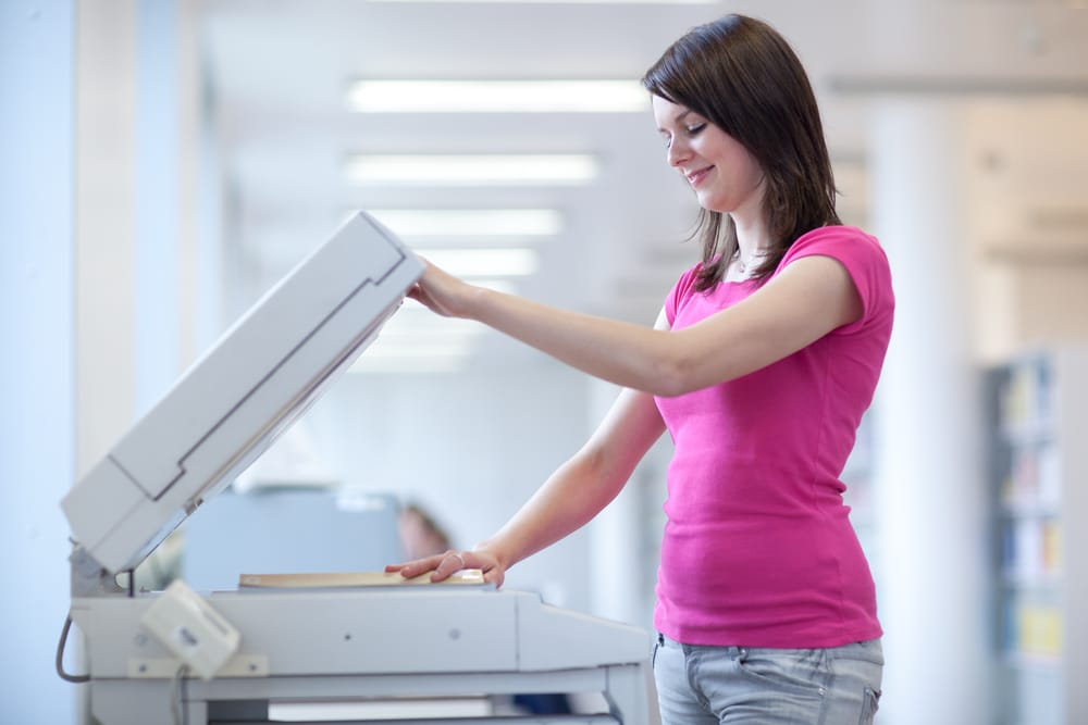 pretty young woman using a copy machine (shallow DOF; color toned image)